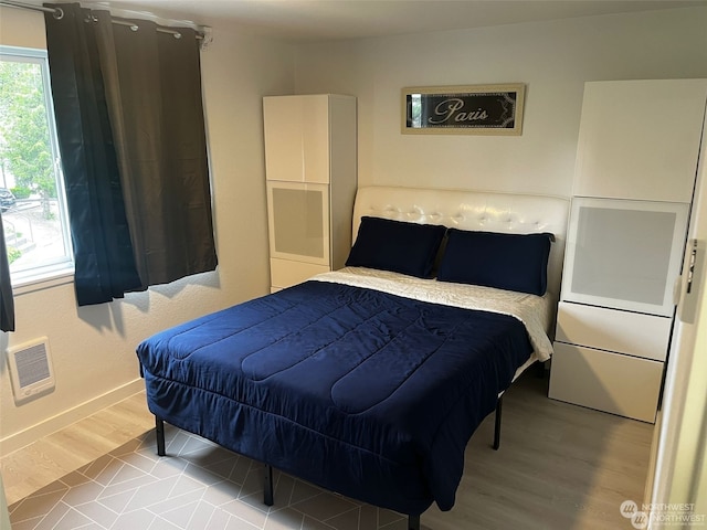 bedroom featuring heating unit and light hardwood / wood-style floors