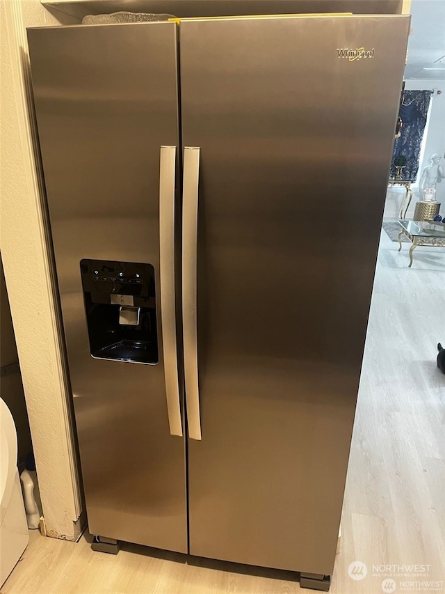 room details with light wood-type flooring and stainless steel refrigerator with ice dispenser