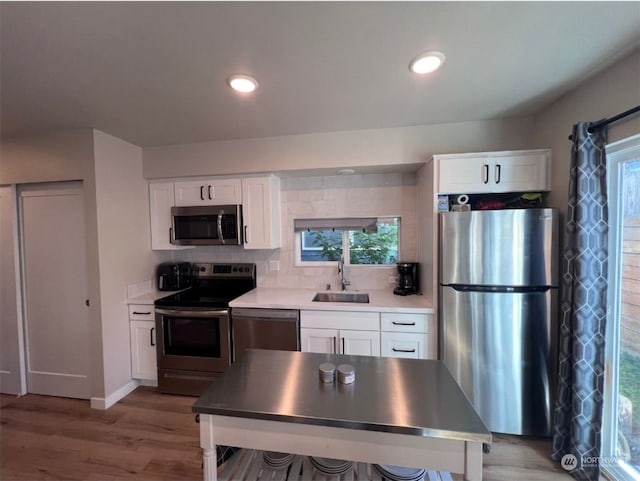 kitchen with white cabinets, stainless steel appliances, and light wood-type flooring