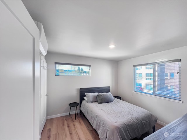 bedroom with light hardwood / wood-style floors and multiple windows