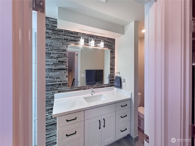 bathroom with vanity, toilet, and decorative backsplash