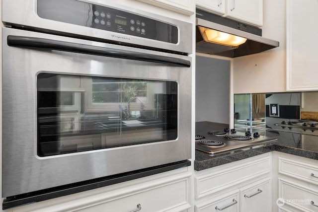 kitchen with cooktop, oven, and white cabinetry