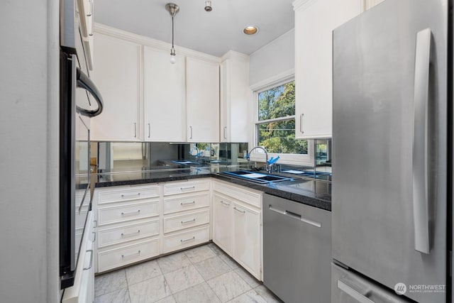 kitchen featuring dark stone counters, white cabinetry, sink, and stainless steel appliances