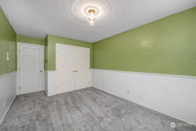 unfurnished bedroom with light colored carpet and a closet