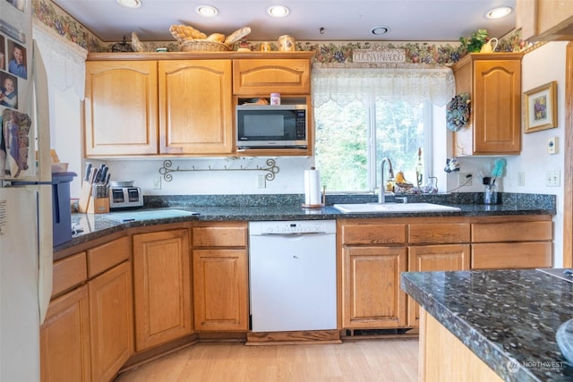 kitchen with white dishwasher, light hardwood / wood-style flooring, sink, and dark stone counters