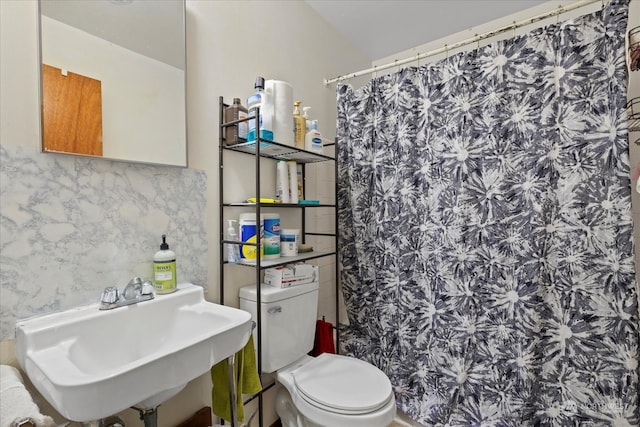 bathroom with toilet, sink, and a shower with curtain