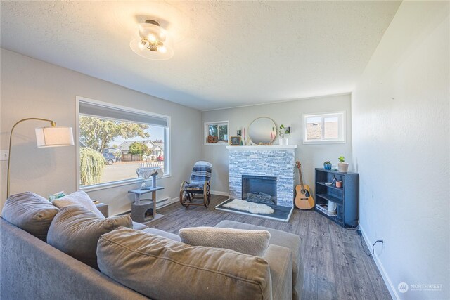 living room featuring a textured ceiling, baseboard heating, a fireplace, and dark hardwood / wood-style flooring