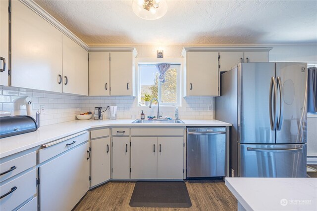 kitchen with appliances with stainless steel finishes, sink, tasteful backsplash, and dark hardwood / wood-style flooring