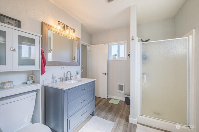 bathroom featuring wood-type flooring, vanity, a shower with shower door, and toilet