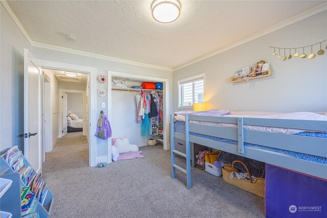 bedroom with a textured ceiling, a closet, crown molding, and carpet