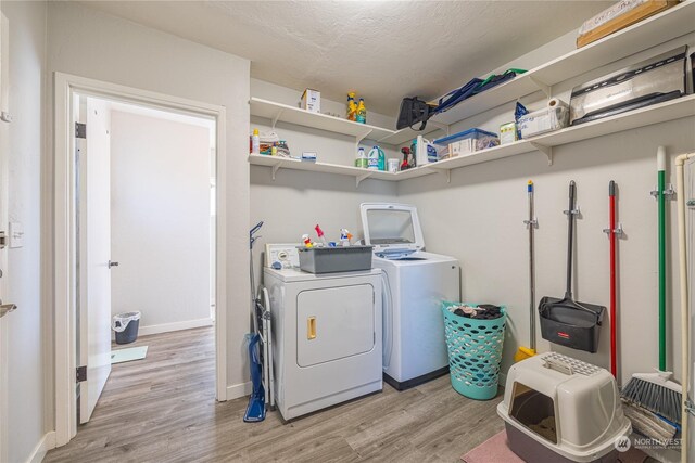 washroom featuring light wood-type flooring, a textured ceiling, and washing machine and dryer