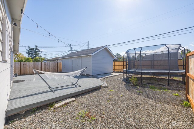 view of yard featuring a trampoline, an outbuilding, and a deck