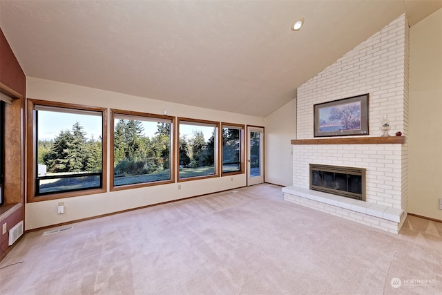 unfurnished living room featuring a healthy amount of sunlight, a fireplace, vaulted ceiling, and light colored carpet