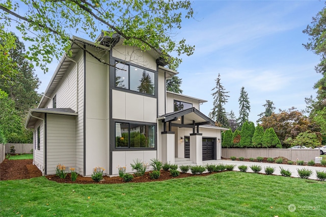 contemporary house with driveway, a front lawn, and fence