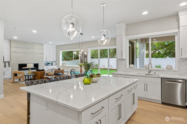 kitchen with dishwasher, a tiled fireplace, sink, and a wealth of natural light