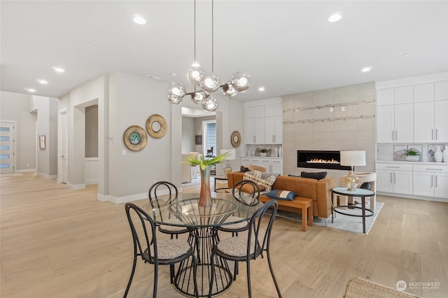 dining space with a tiled fireplace and light hardwood / wood-style floors