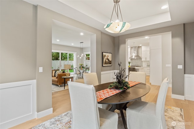 dining area featuring a raised ceiling and light hardwood / wood-style floors