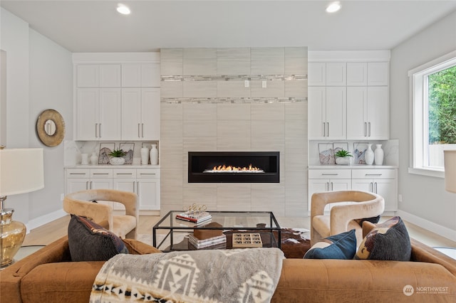 living room featuring light wood-type flooring and a tiled fireplace