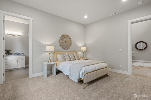 bedroom with ensuite bath and light colored carpet