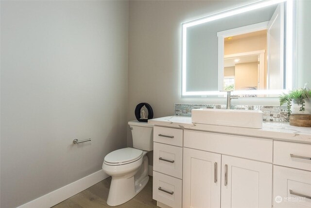 bathroom with wood-type flooring, vanity, and toilet