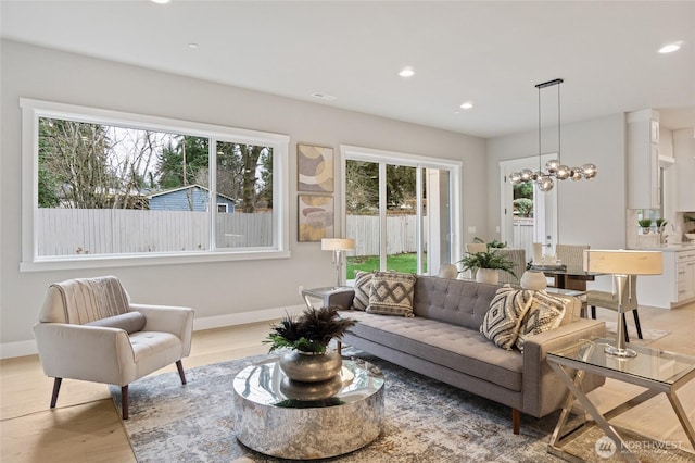 living room featuring baseboards, an inviting chandelier, light wood-style flooring, and recessed lighting