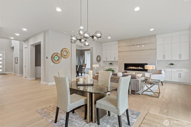 dining area featuring light wood finished floors, recessed lighting, baseboards, and a tile fireplace