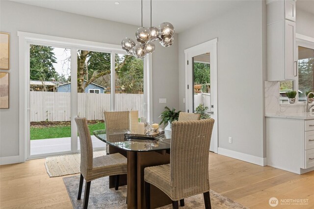 dining space featuring baseboards, light wood-style flooring, and a healthy amount of sunlight