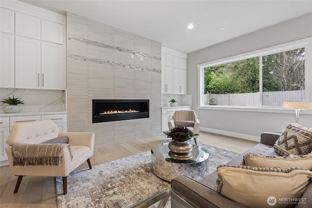 living room with light wood-style floors, a fireplace, baseboards, and recessed lighting