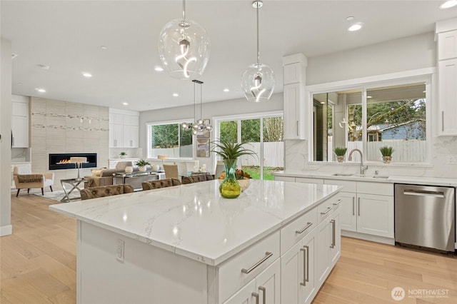 kitchen featuring decorative light fixtures, a fireplace, a kitchen island, a sink, and dishwasher