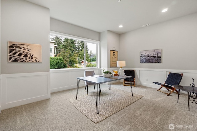 office space featuring recessed lighting, light colored carpet, a decorative wall, visible vents, and wainscoting