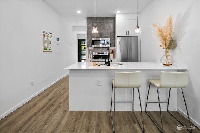 kitchen with tasteful backsplash, white cabinetry, dark hardwood / wood-style floors, decorative light fixtures, and stainless steel appliances