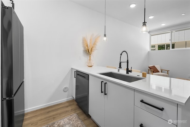 kitchen with white cabinets, dark hardwood / wood-style floors, stainless steel appliances, sink, and decorative light fixtures