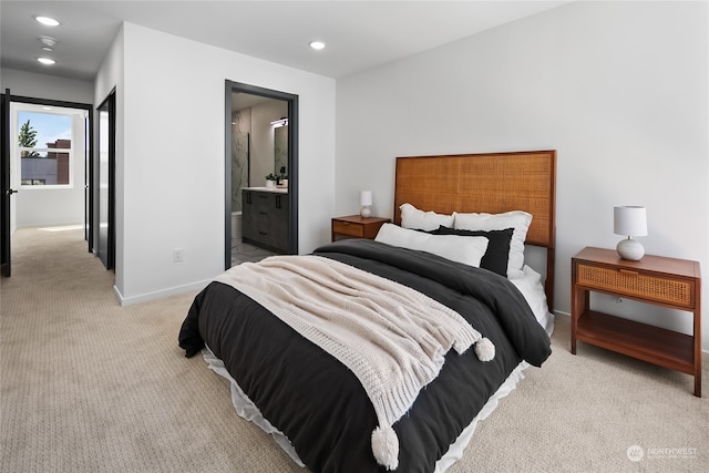 bedroom featuring ensuite bathroom and light carpet