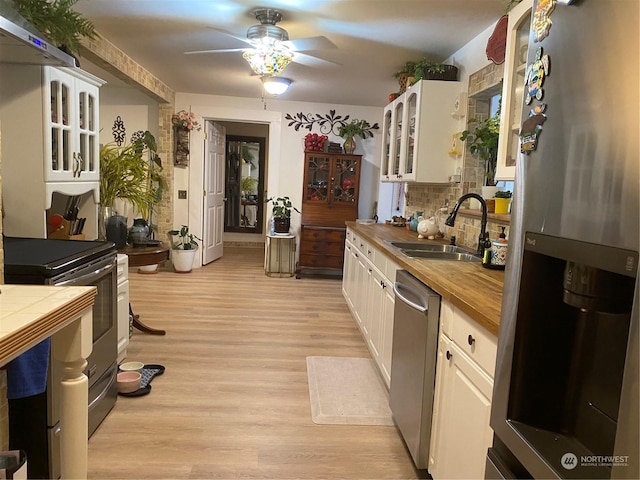 kitchen with a sink, wood counters, stainless steel appliances, light wood-type flooring, and ceiling fan