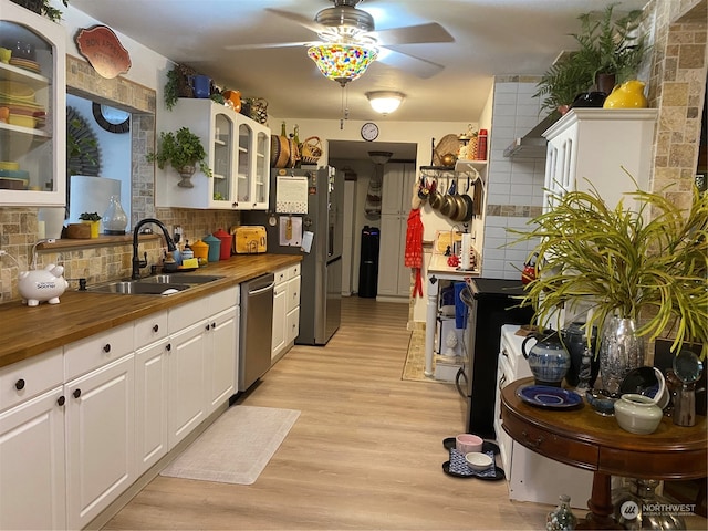 kitchen featuring sink, light hardwood / wood-style flooring, dishwasher, butcher block counters, and decorative backsplash