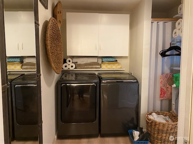 clothes washing area featuring cabinets, light hardwood / wood-style flooring, and washer and clothes dryer