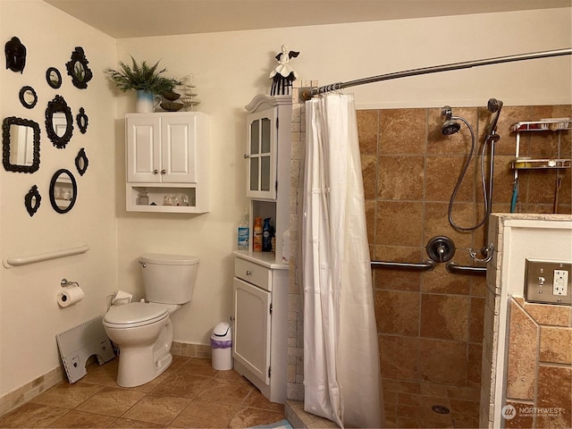 full bath featuring tile patterned floors, toilet, baseboards, and tiled shower