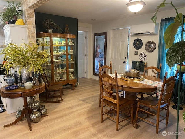 dining space with a wall unit AC and light wood-style floors