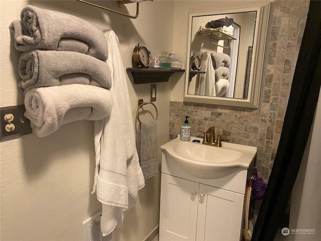 bathroom with decorative backsplash, vanity, and visible vents