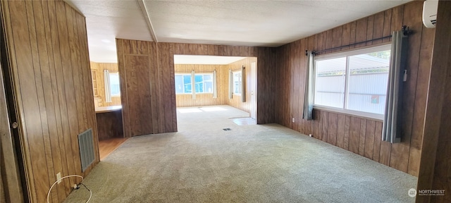 unfurnished room with a wall unit AC, light carpet, and wooden walls