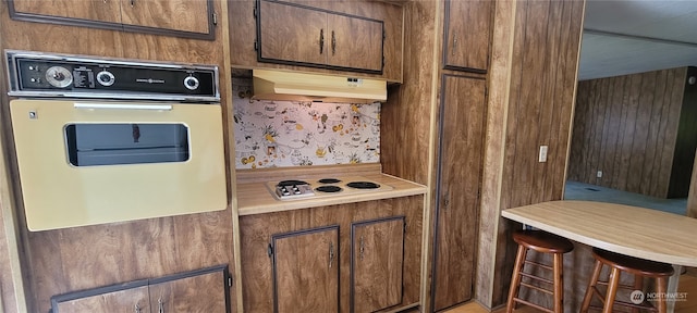 kitchen featuring wall oven, a kitchen breakfast bar, and white electric stovetop