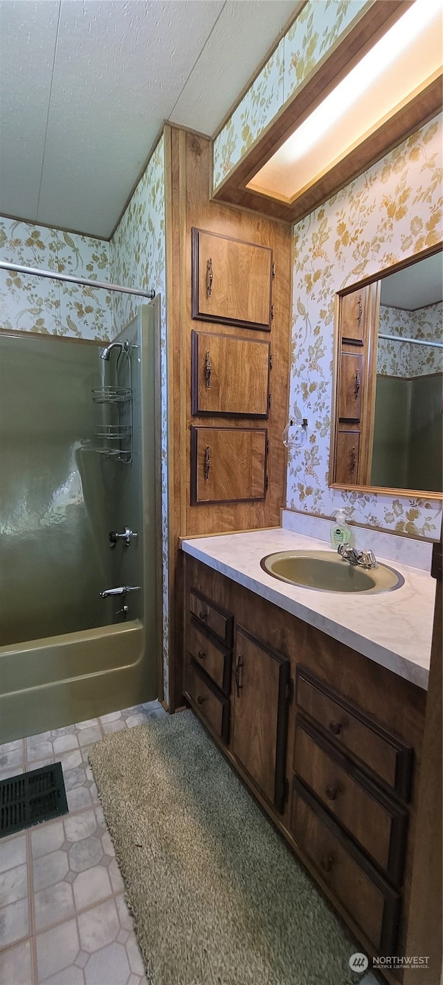 bathroom featuring vanity, bathtub / shower combination, and a textured ceiling