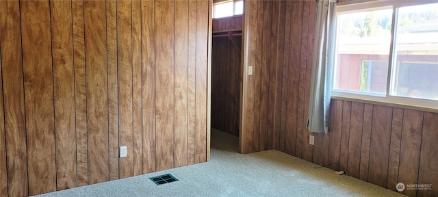 carpeted empty room featuring wooden walls