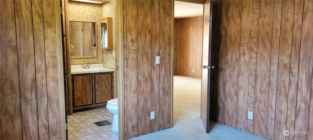 bathroom featuring vanity, toilet, and wood walls