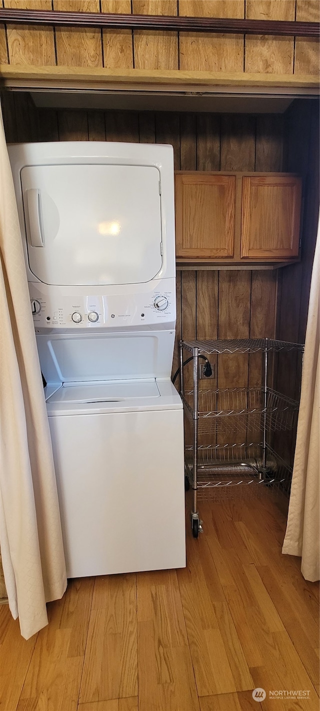 washroom with stacked washer and clothes dryer and light wood-type flooring