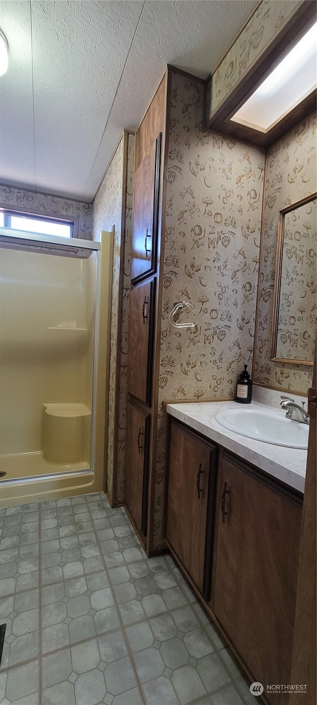 bathroom with vanity, a textured ceiling, and walk in shower