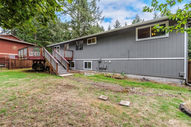 back of property featuring a wooden deck and a yard