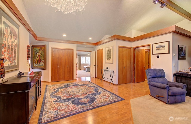 entryway with light wood-type flooring, a chandelier, and vaulted ceiling