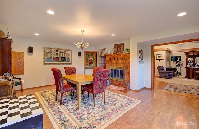 dining space featuring an inviting chandelier, a fireplace, and light wood-type flooring