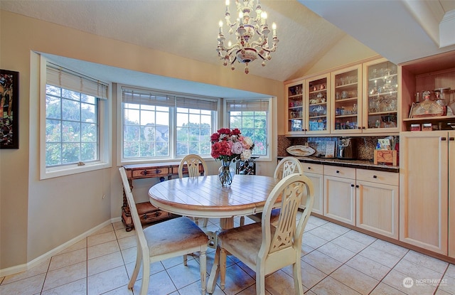 tiled dining room with a notable chandelier, a textured ceiling, vaulted ceiling, and plenty of natural light